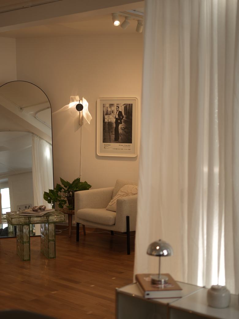 Coin salon : fauteuil clair, affiche encadrée et miroir arqué